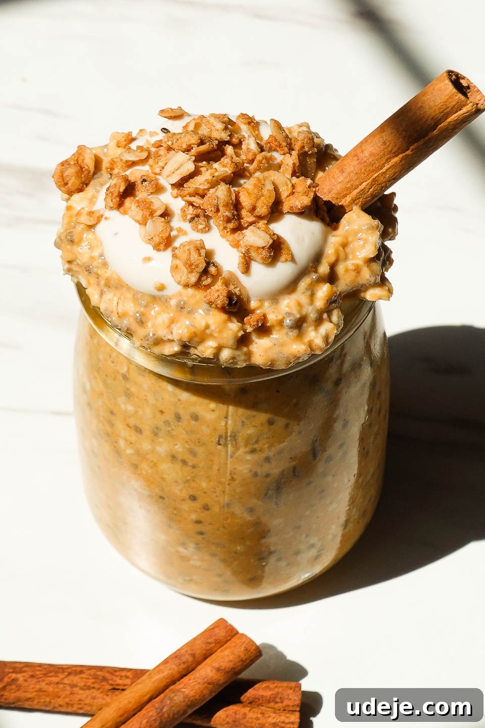 Autumn Spiced Overnight Oats 2 Creamy pumpkin pie overnight oats in a glass jar topped with granola, a swirl of non-dairy yogurt, and a sprinkle of spices, showcasing a healthy and appealing breakfast.