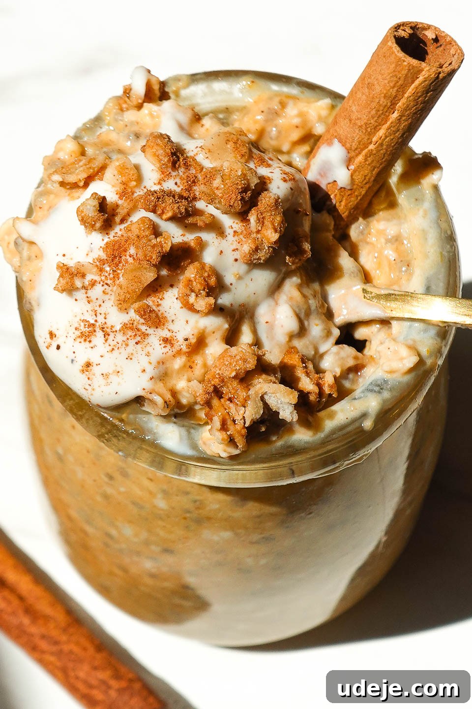 Autumn Spiced Overnight Oats 4 Close up of a glass jar filled with pumpkin pie overnight oats, generously topped with creamy yogurt, crunchy granola, and a light dusting of cinnamon, ready to eat.