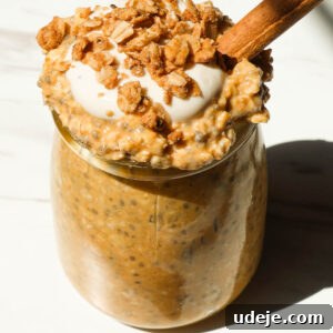 Creamy pumpkin pie overnight oats in a glass jar topped with granola and yogurt, a perfect autumnal breakfast.