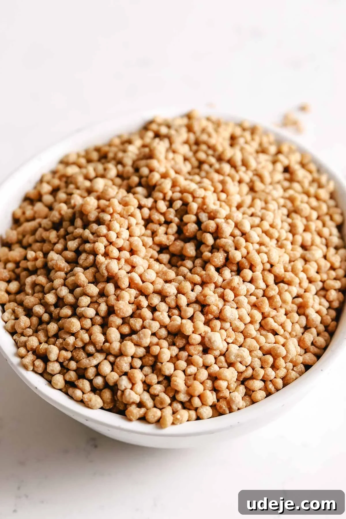 Uncooked Palestinian maftoul, showcased in a pristine small white bowl, highlighting its distinctive grain size and texture before preparation.