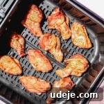 Quick Crispy Pomegranate Air Fryer Wings 6 Ten raw chicken wings with pomegranate sauce in a black air fryer basket on a light pink background