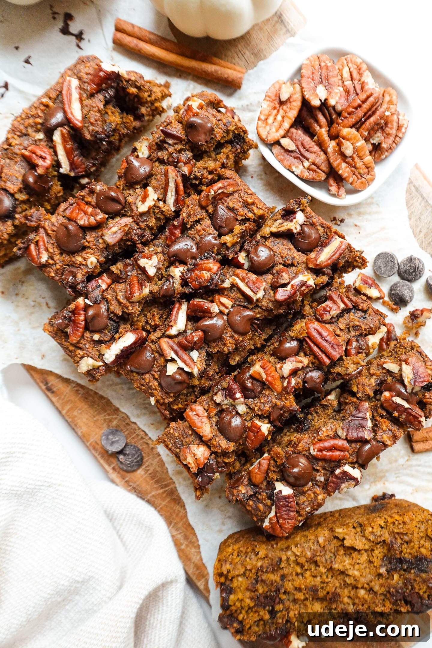 Warm Spiced Vegan Gluten Free Pumpkin Banana Bread 2 A freshly baked loaf of pumpkin spice banana bread with a golden crust, topped with pecans and chocolate chips.