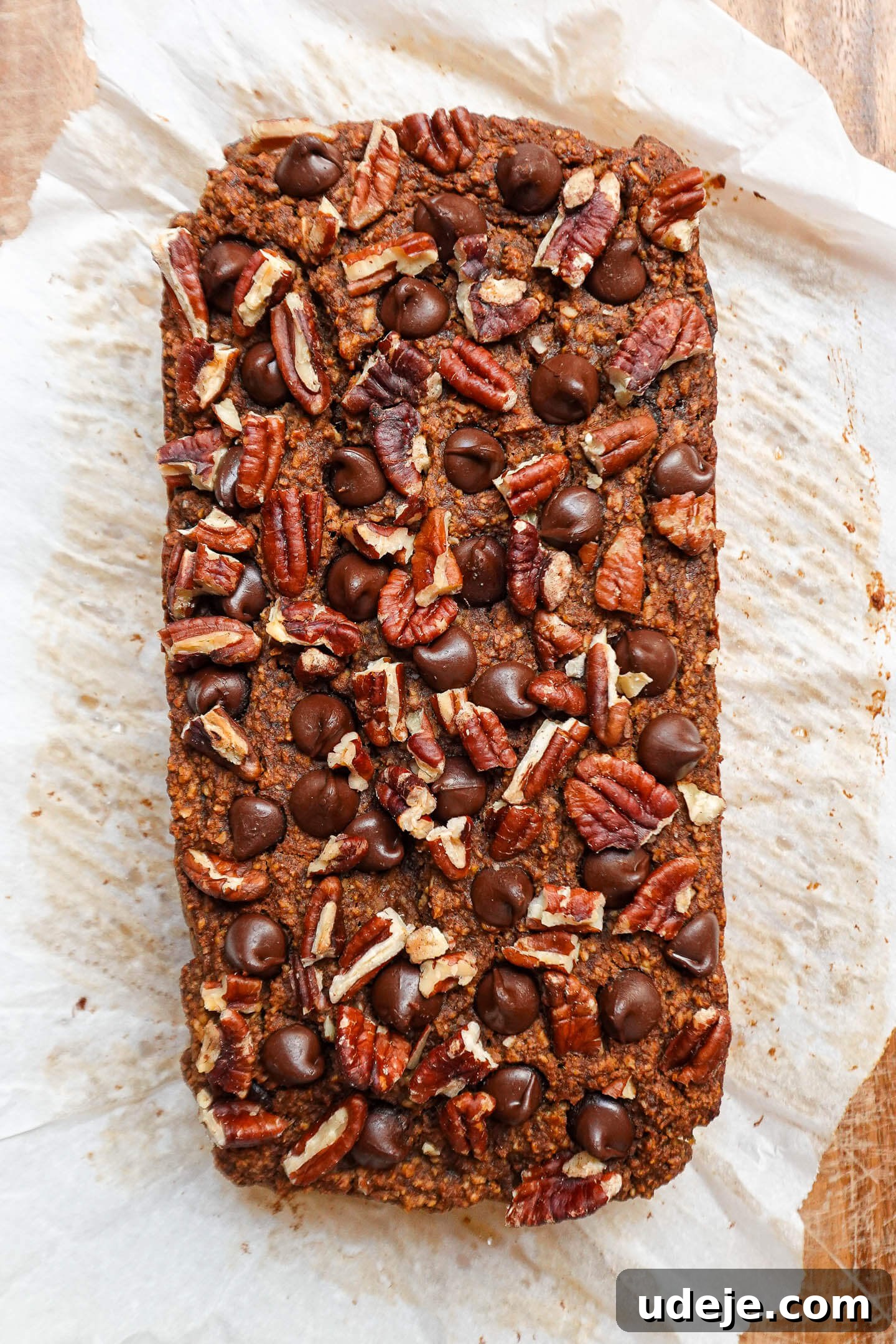 Warm Spiced Vegan Gluten Free Pumpkin Banana Bread 4 A freshly baked loaf of pumpkin spice banana bread with a golden crust, topped with pecans and chocolate chips