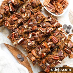 A freshly baked loaf of pumpkin spice banana bread with a golden crust, topped with pecans and chocolate chips.