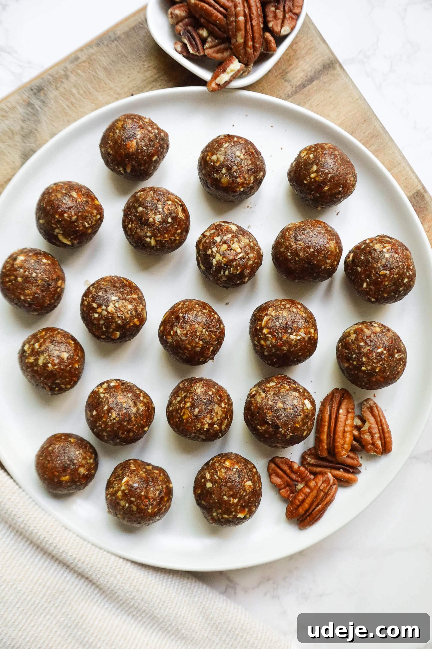 Pecan Pie Power Bites 2 Healthy vegan Pecan Pie Energy Balls stacked on a plate on a wooden board