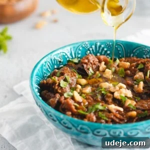 Exquisite Mediterranean Roasted Eggplant Dip served in a blue bowl, elegantly garnished with toasted walnuts and fresh parsley. The inviting texture and rich colors promise a delightful culinary experience.