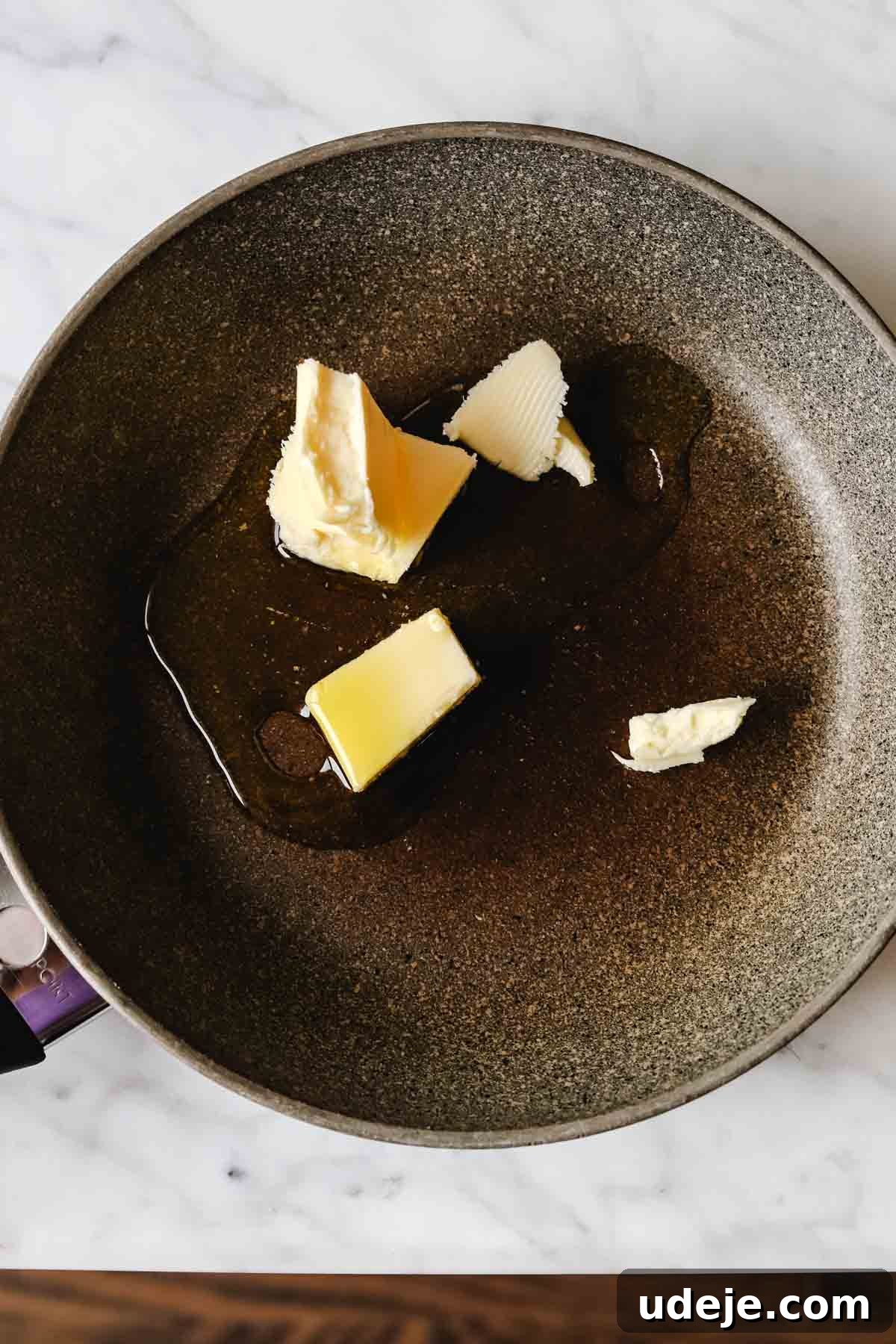 A small non-stick skillet on the stovetop, with unsalted butter gently melting and bubbling, ready for the next ingredient.