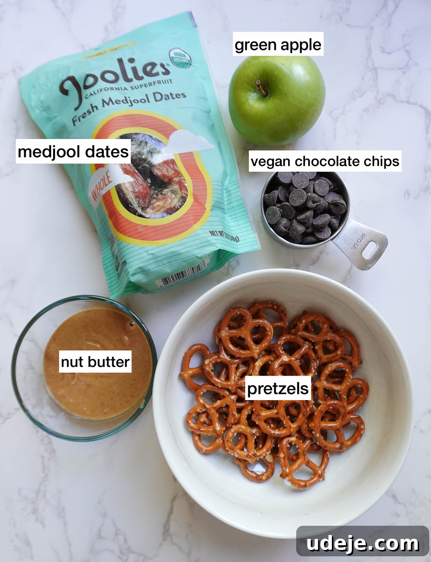 Wholesome Apple Date Caramel Bark 3 Overhead photo of recipe ingredients: Medjool dates, apples, pretzels, peanut butter, and vegan chocolate chips on a counter