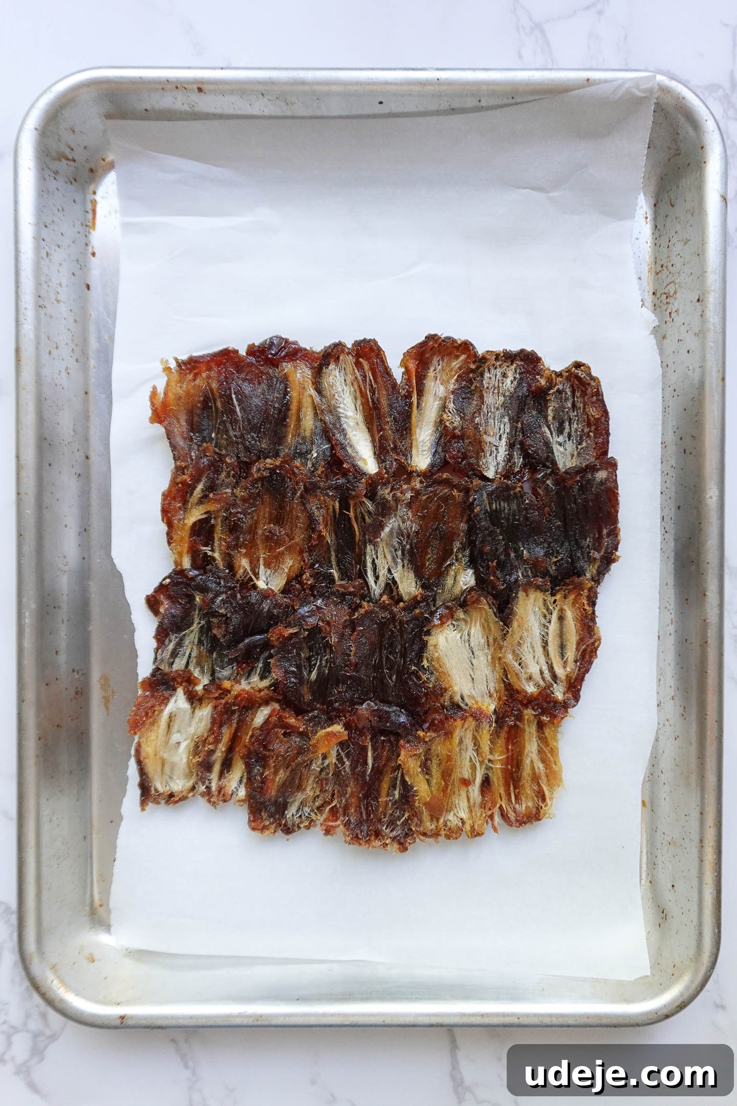 Wholesome Apple Date Caramel Bark 4 Pitted Medjool dates pressed onto a parchment-lined baking sheet to form the base for date bark