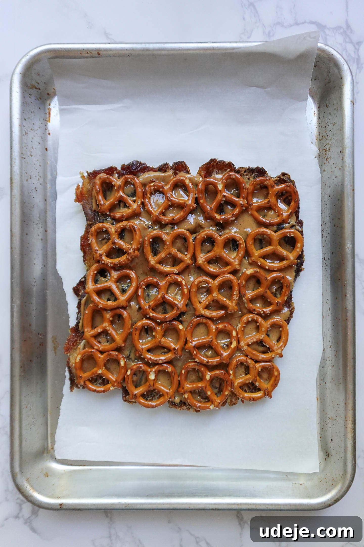 Wholesome Apple Date Caramel Bark 5 Layer of crushed pretzels and creamy peanut butter spread over Medjool dates on baking sheet