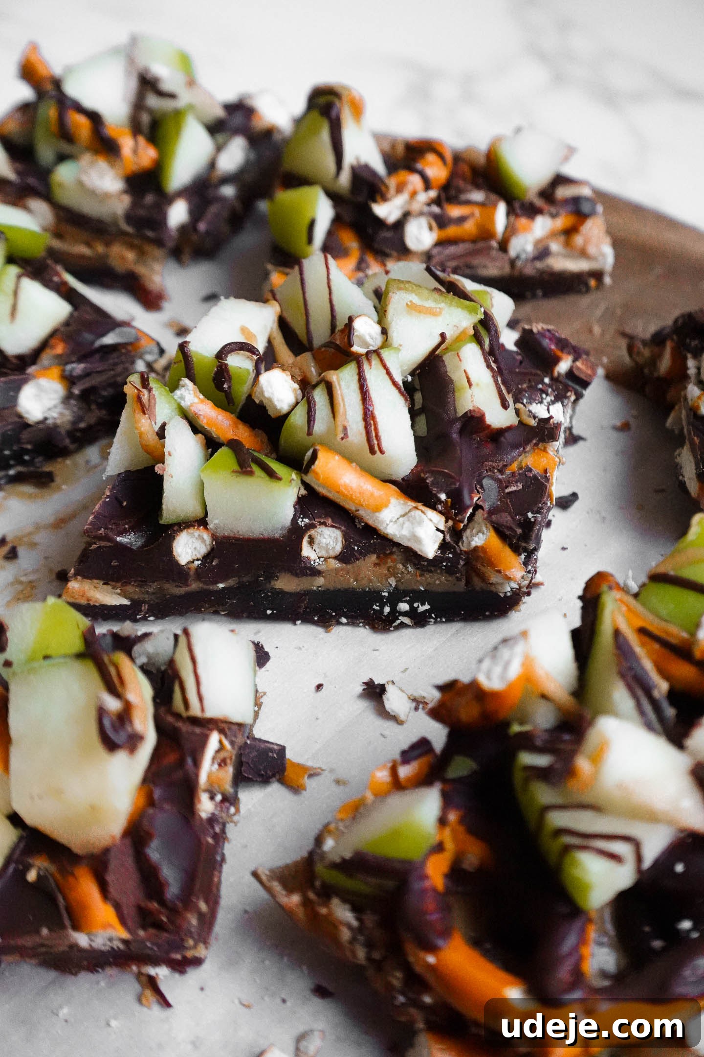 Wholesome Apple Date Caramel Bark 8 Close-up view of sliced caramel apple date bark showing layers of dates, pretzels, apples, and melted chocolate.