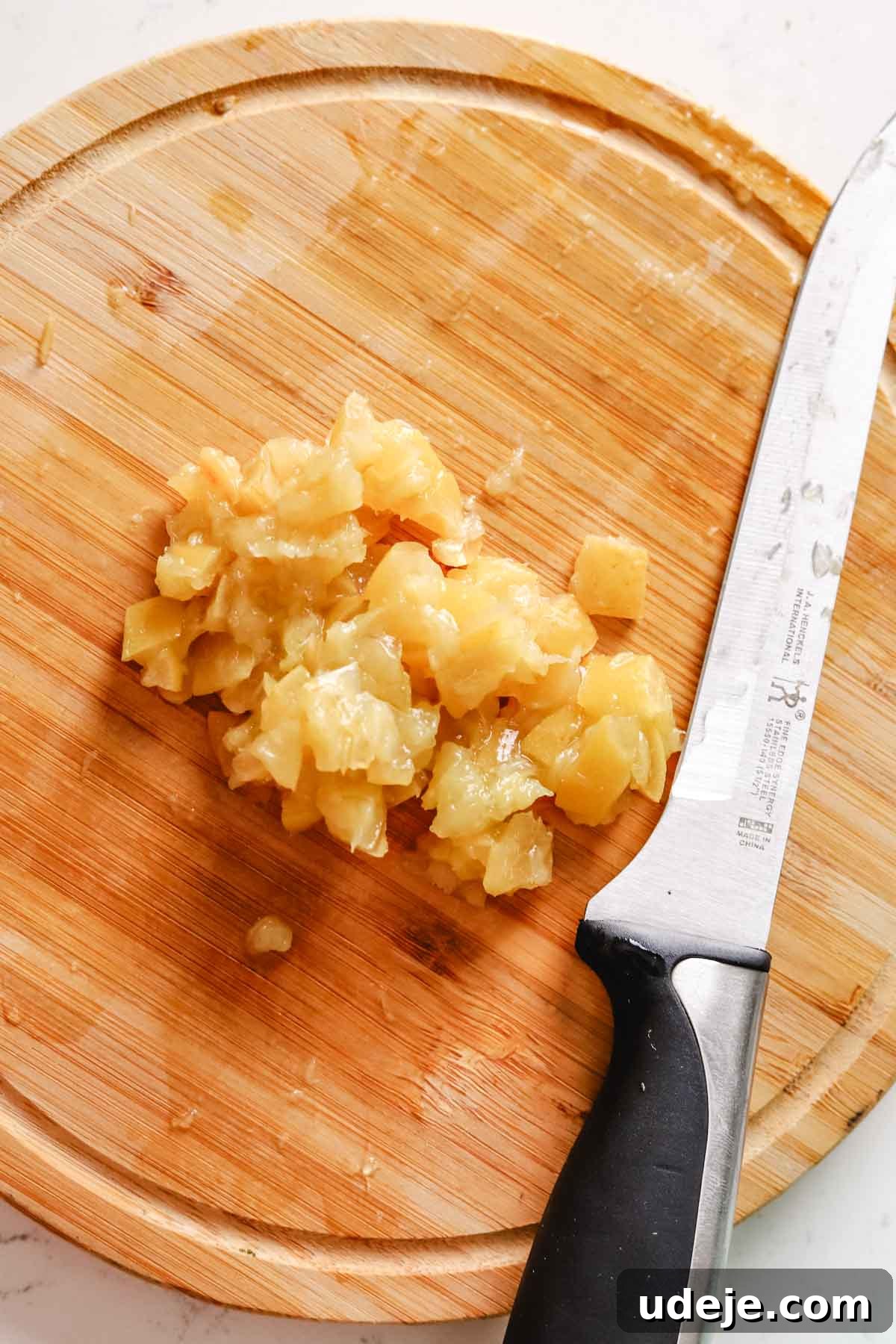 Golden Crispy Moroccan Oven Chicken 4 preserved lemons chopped on a round wooden cutting board with a large knife on a white marble surface