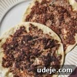 Two kofta smash tacos cooked on a beige plate on a pink background