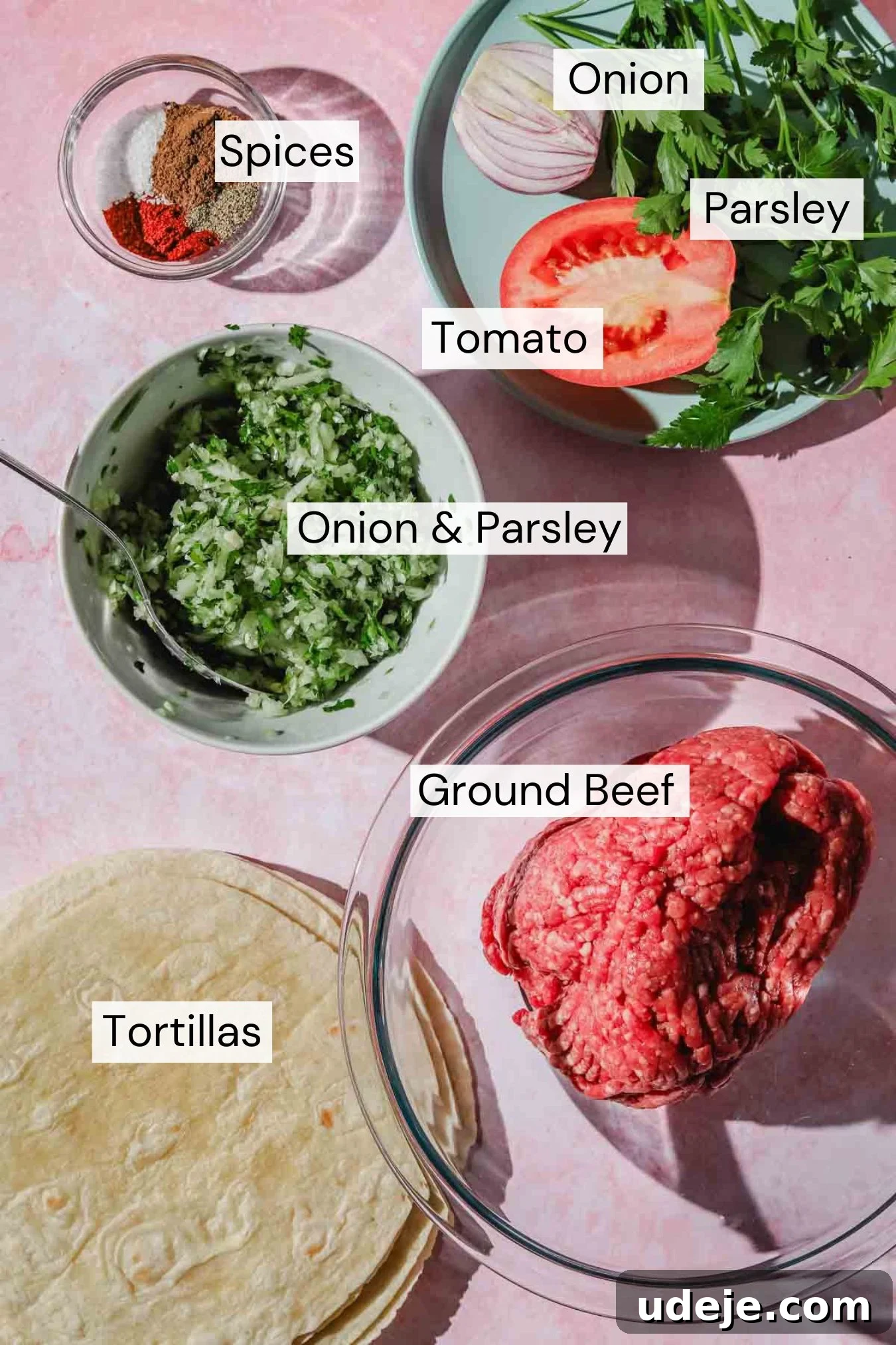 Ingredients for Kofta Smash Tacos laid out: ground beef, small tortillas, a whole onion, fresh parsley, and various spices.