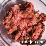 Ground beef kofta mixture in glass bowl on pink background