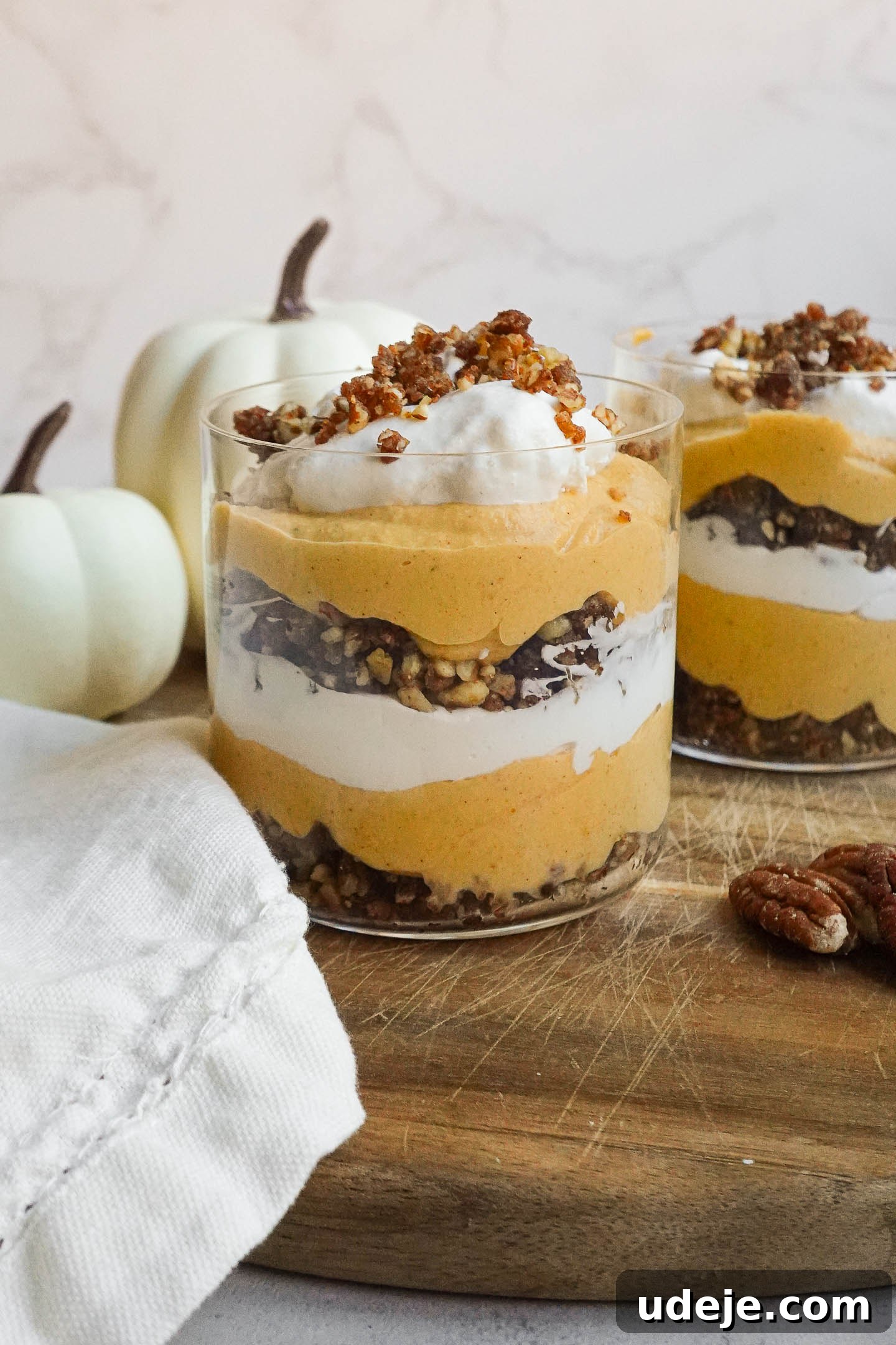 Effortless Vegan Pumpkin Cheesecake Trifle 2 Layered vegan pumpkin cheesecake trifle in a glass jar with pecan-date crumble and coconut whipped cream