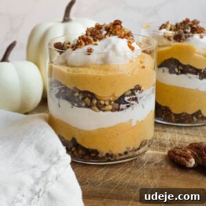 Effortless Vegan Pumpkin Cheesecake Trifle 7 Layered vegan pumpkin cheesecake trifle in a glass jar with pecan-date crumble and coconut whipped cream