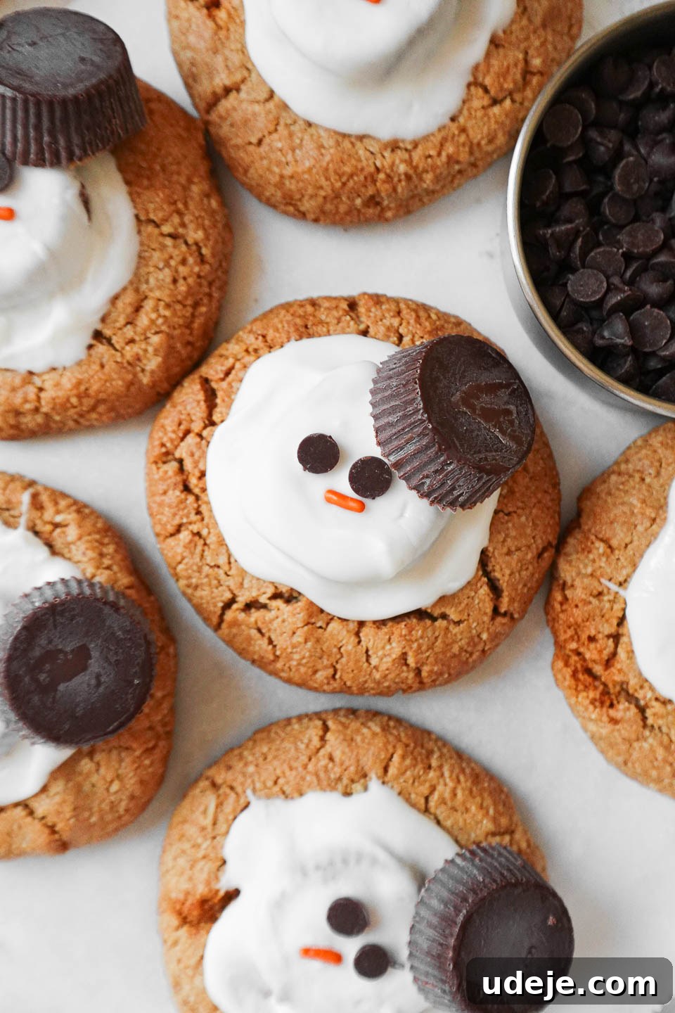 Whimsical Vegan Gluten Free Melted Snowman Cookies 2 Vegan melted snowman peanut butter cookies decorated with white chocolate, peanut butter cups, and mini chocolate chips, arranged festively for the holidays.