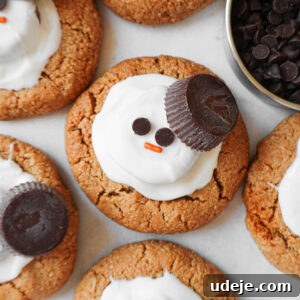 Vegan melted snowman peanut butter cookies decorated with white chocolate, peanut butter cups, and mini chocolate chips