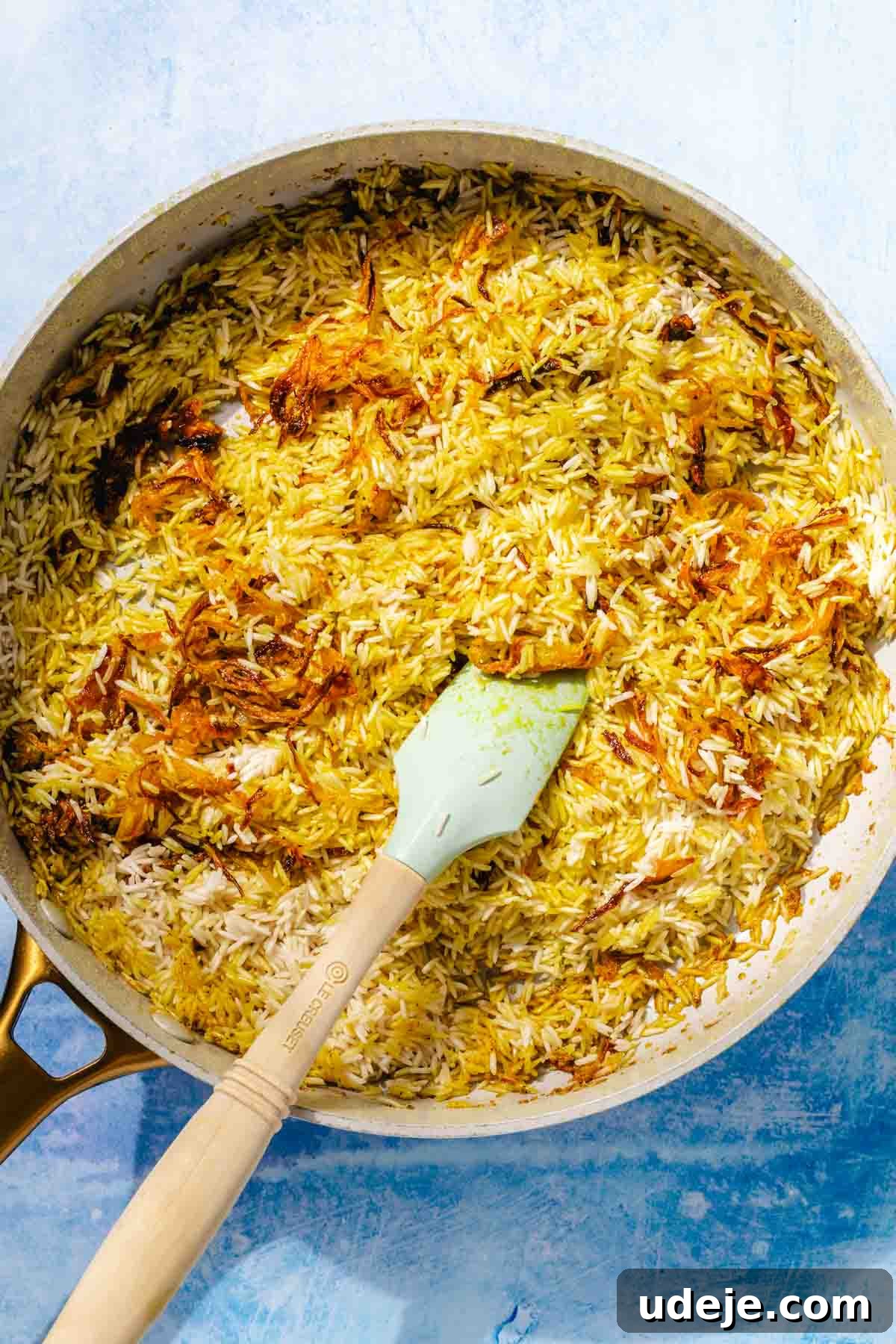 Fragrant Middle Eastern Fish Pilaf 18 Rice with spiced fried onions in a saute pan with a blue spatula