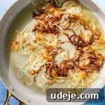 Fragrant Middle Eastern Fish Pilaf 22 Browned crispy onions in a saute pan with oil on a blue background