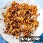 Fragrant Middle Eastern Fish Pilaf 23 Crispy fried onions on a paper towel on a gold rimmed white plate on a blue background