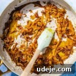 Fragrant Middle Eastern Fish Pilaf 27 crispy onions being fried with spices in a saute pan with a blue spatula on a blue background