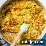 Fragrant Middle Eastern Fish Pilaf 28 Rice with spiced fried onions in a saute pan with a blue spatula
