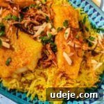 Fragrant Middle Eastern Fish Pilaf 29 Blue patterned platter with yellow rice, fried cod fillets, garnished with toasted slivered almonds, fried onions and parsley on a blue background