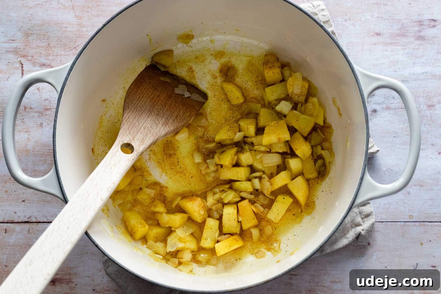 Middle Eastern Lentil Soup Two Ways 4 Diced onions and potatoes being gently cooked in a pot with oil and a medley of aromatic spices, creating a flavorful base for the soup.