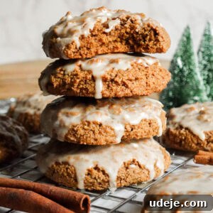 Stack of round, soft iced gingerbread cookies with a bite taken out of the top cookie, showing a fluffy interior.