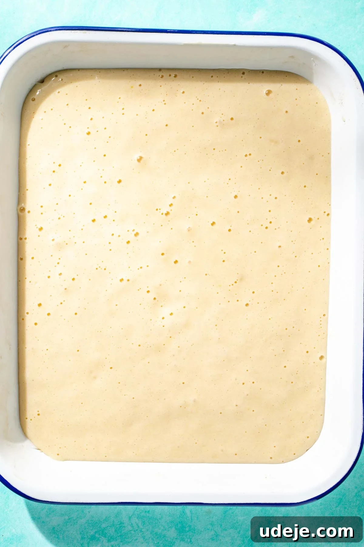 Heavenly Turkish Milk Cake 13 Cake batter poured into white baking dish on a blue background