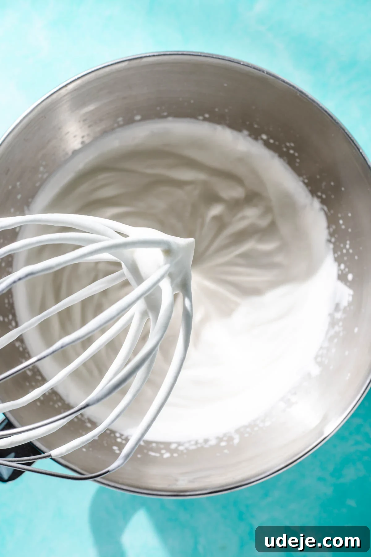 Heavenly Turkish Milk Cake 23 Whipped cream in a metal bowl with a whisk at the top on a blue background