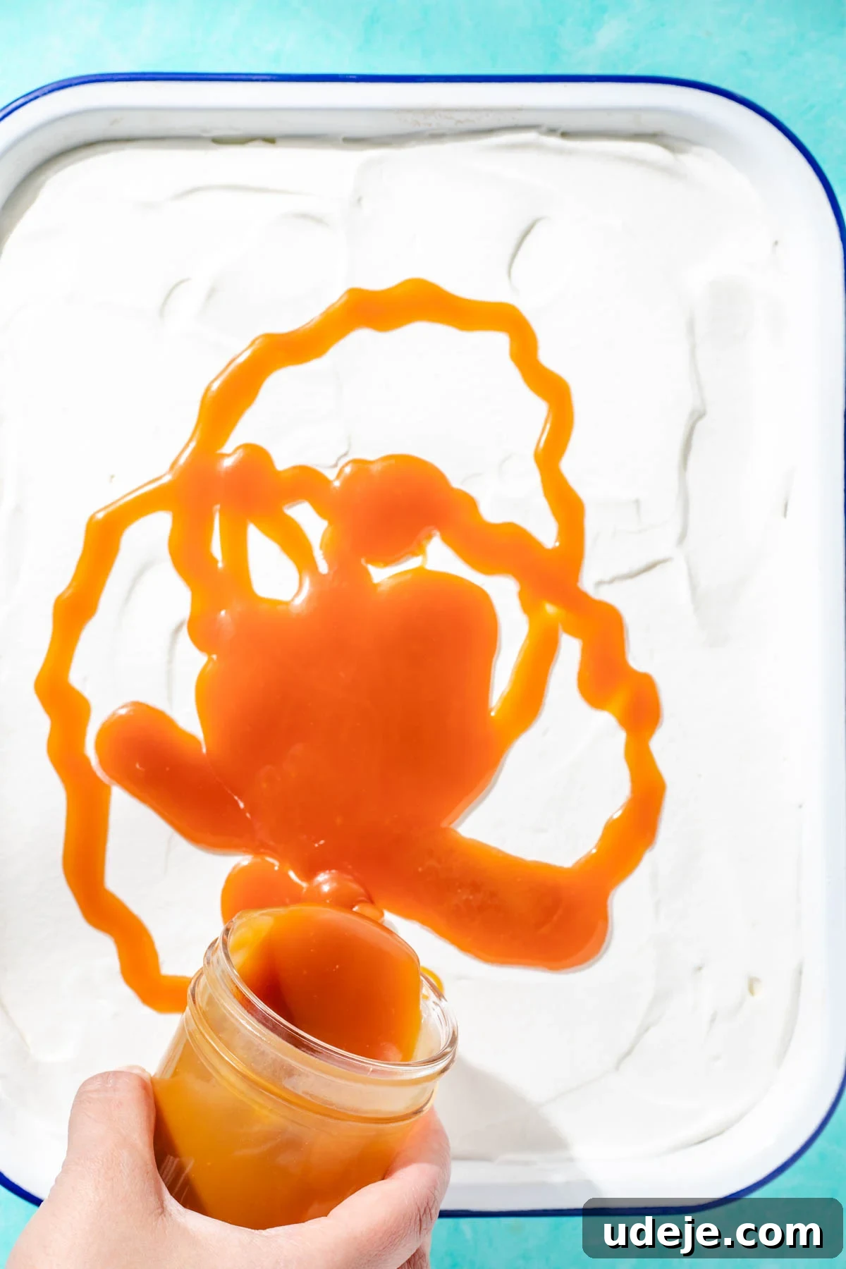 Heavenly Turkish Milk Cake 26 Caramel sauce being drizzled over cake in white baking pan on a blue background
