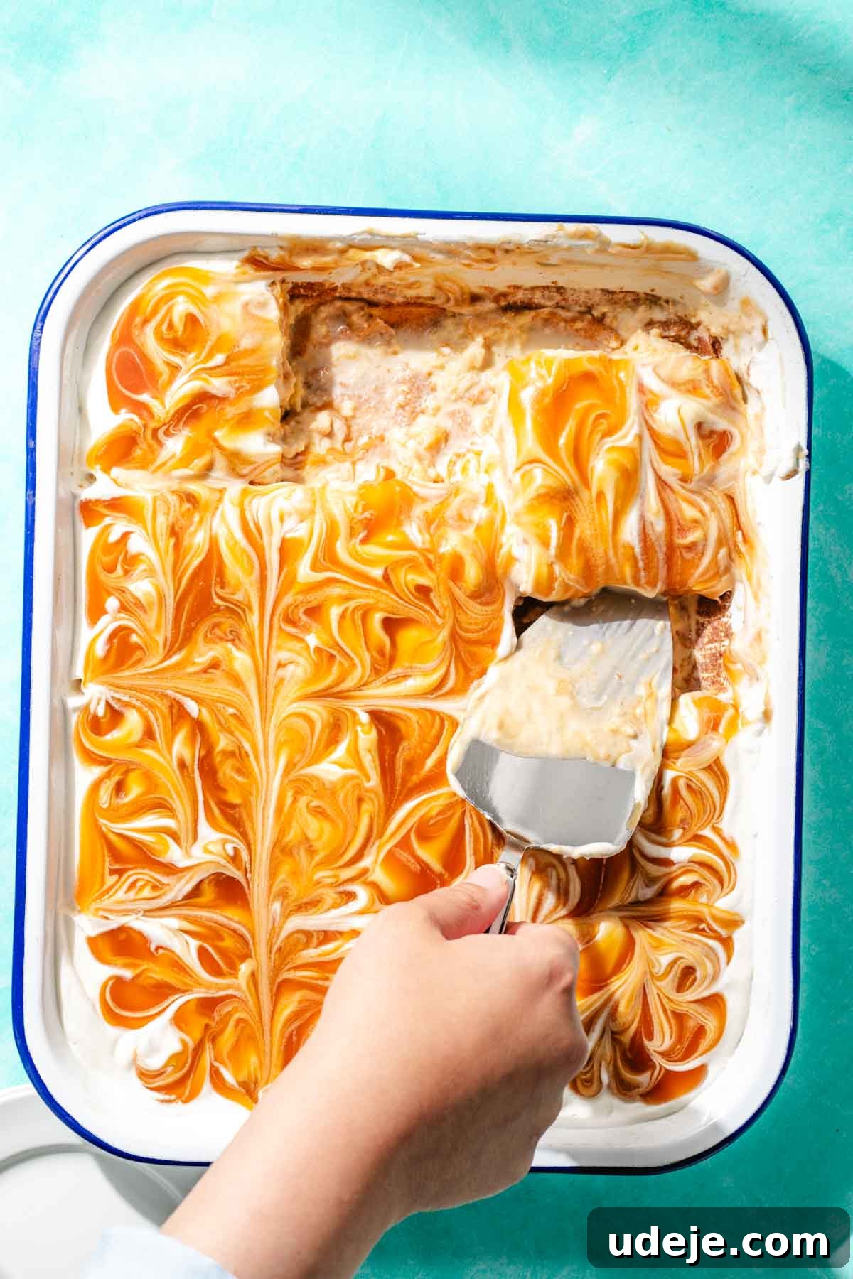 Heavenly Turkish Milk Cake 28 Turkish Tres leches cake in a white pan with a cake server lifting a slice out of the pan on a blue background