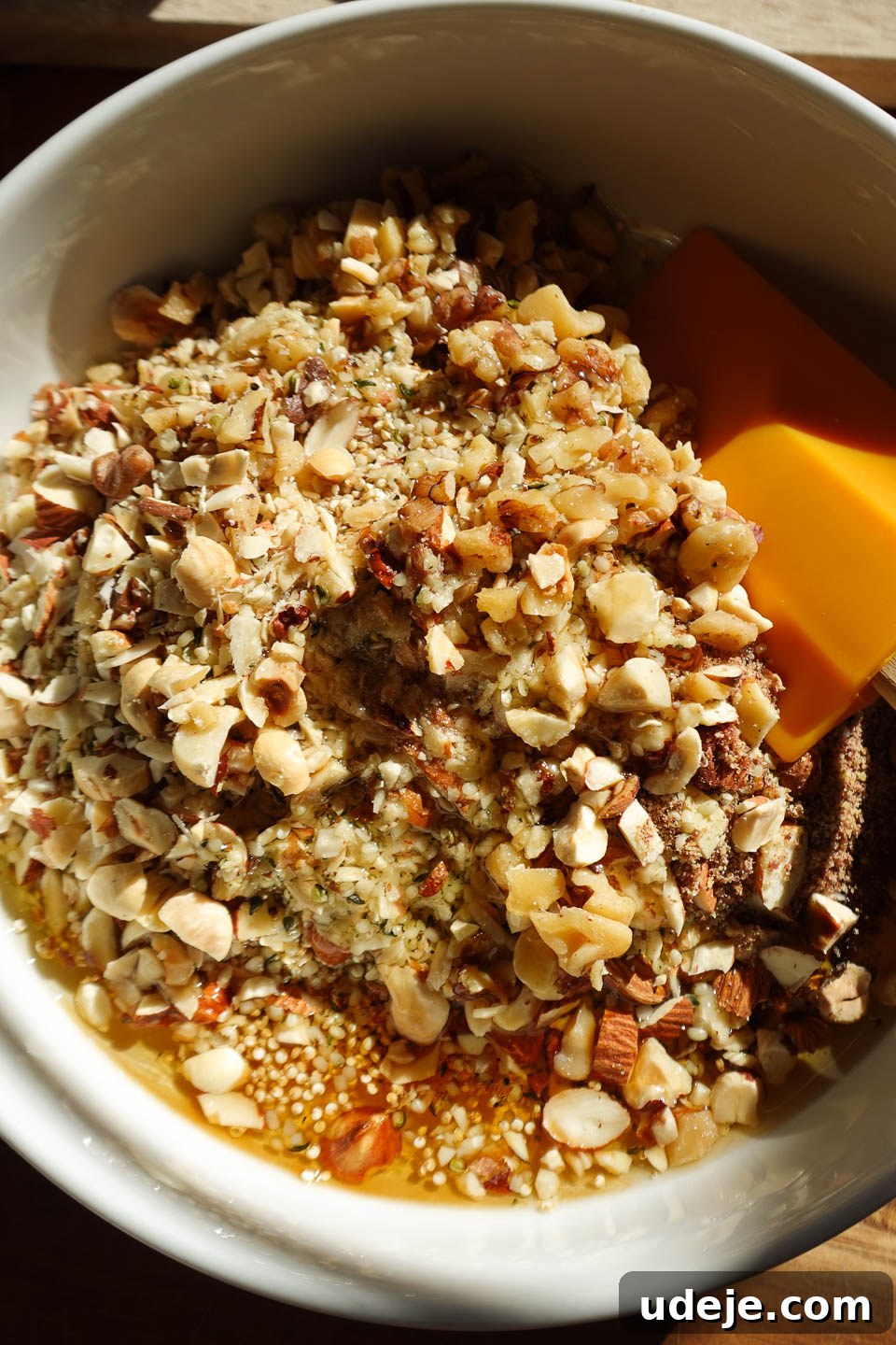 Wholesome Chocolate Quinoa Crunch Bark 3 A large bowl filled with a mix of hazelnuts, almonds, pecans, chia seeds, hemp seeds, and maple syrup, ready to be stirred, highlighting the wholesome ingredients.