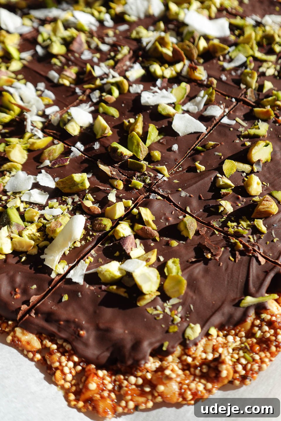 Wholesome Chocolate Quinoa Crunch Bark 4 Chocolate quinoa bark garnished with shredded coconut and flaky sea salt, perfectly broken into pieces for snacking, emphasizing its delicious texture.