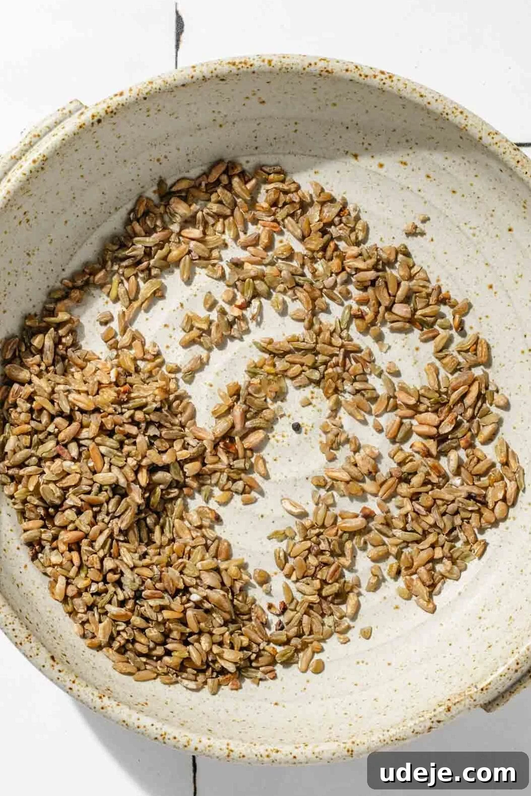 Silky Freekeh Bean Fiesta 4 Uncooked freekeh grains in a small beige bowl, slightly spread apart and being picked through