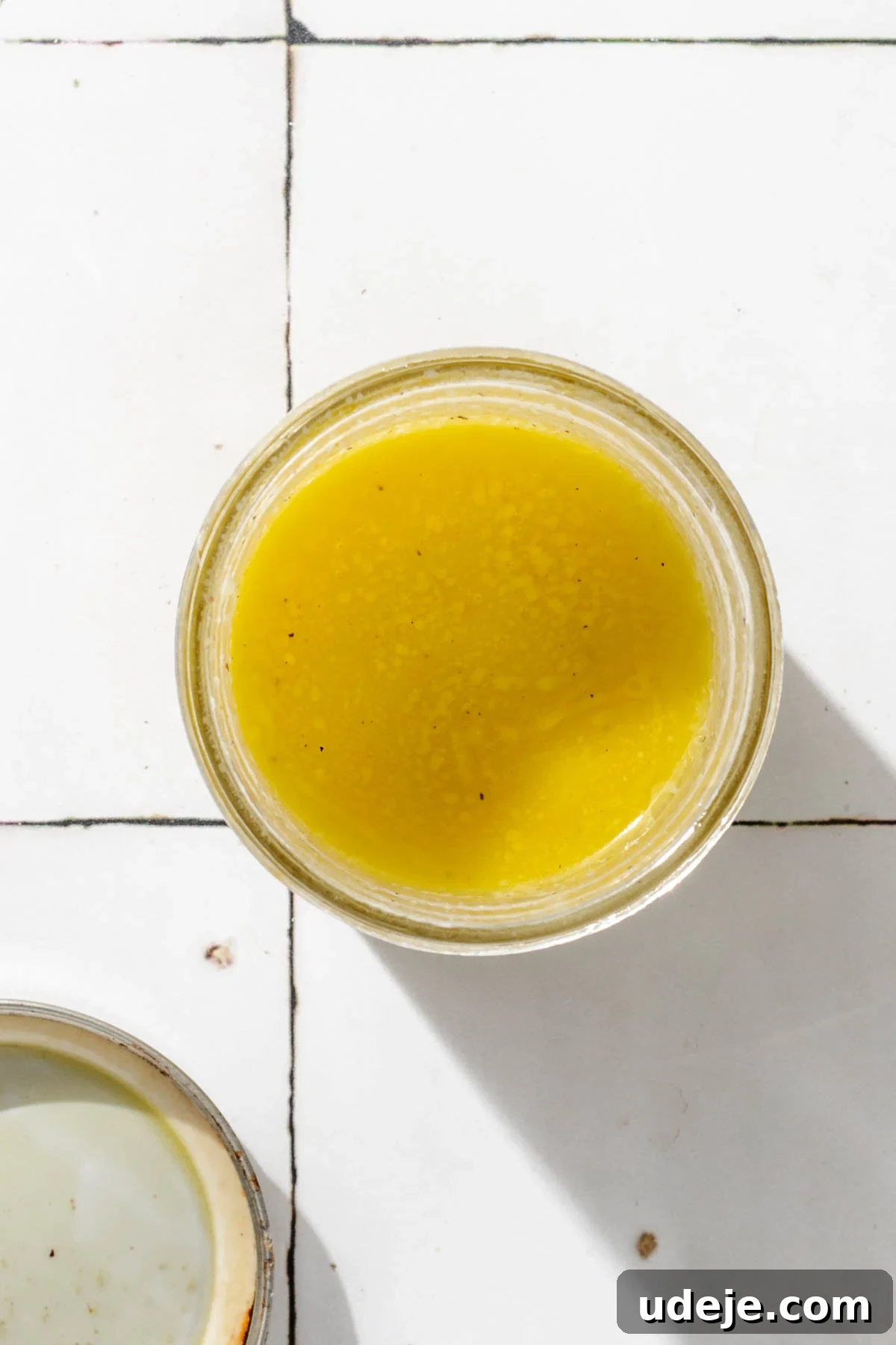 Silky Freekeh Bean Fiesta 10 A honey mustard salad dressing that is bright yellow in a small glass jar, with the lid next to it