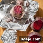 Vibrant Beetroot Yogurt Salad 11 Beets with the tops cut off and one placed in foil and sprinkled with salt on a wooden cutting board on a white tiled background