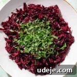 Vibrant Beetroot Yogurt Salad 13 Grated beet in a white salad bowl with chopped mint on top on a green background