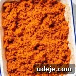 Mixed bulgur with kisir dressing in a white, blue rimmed baking pan on a white tiled surface
