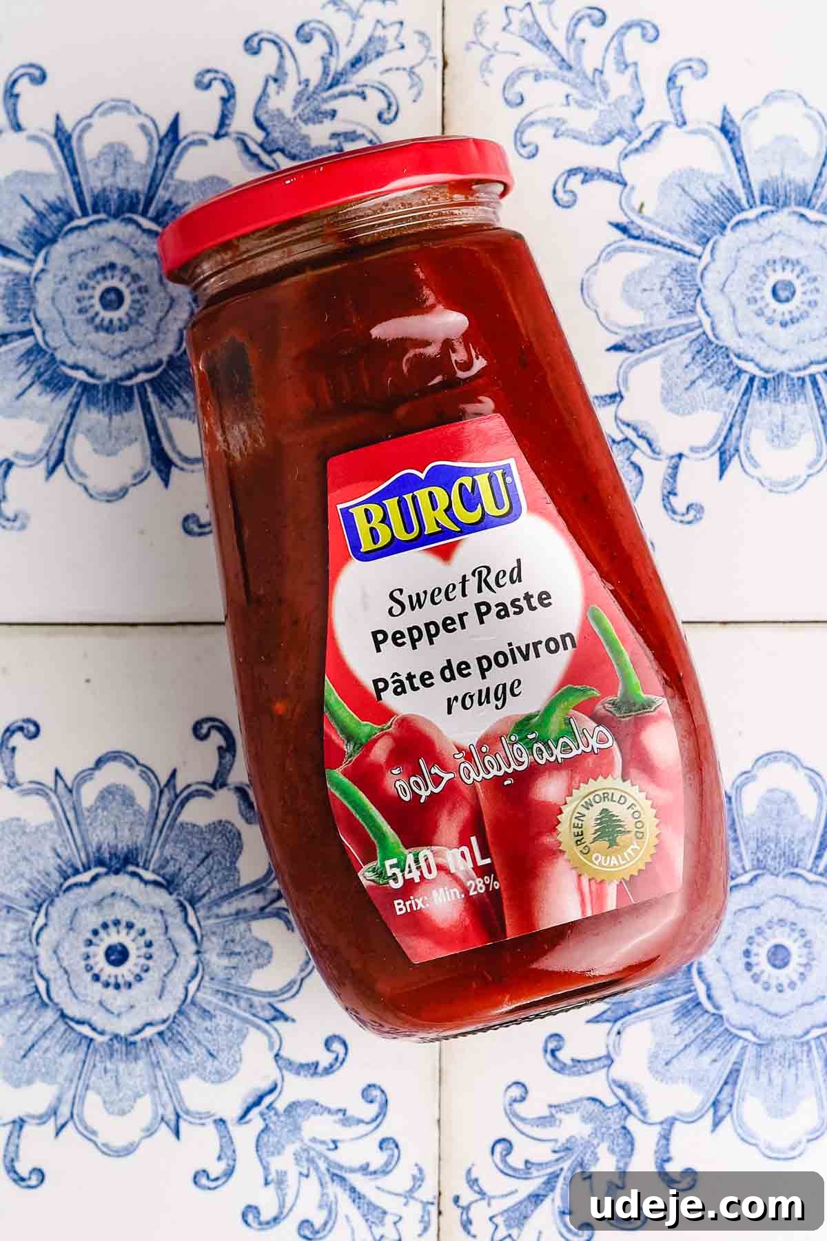 Fast 20-Minute Turkish Bulgur Kisir 4 A vibrant close-up of Turkish sweet red pepper paste, a rich, reddish-orange condiment, presented in a small bowl against a backdrop of traditional blue patterned tiles, highlighting its authentic appeal.