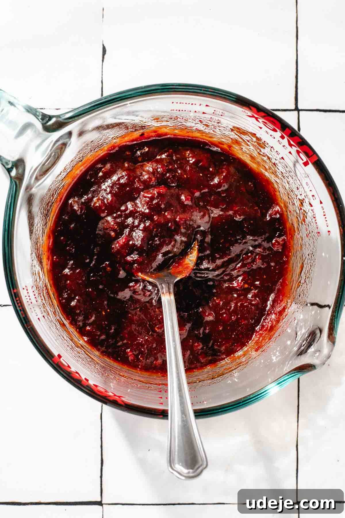 Fast 20-Minute Turkish Bulgur Kisir 8 The Kisir dressing, now perfectly mixed into a rich, thick paste, resting in a glass measuring cup with a spoon, ready to be incorporated into the bulgur, on a white tiled surface.