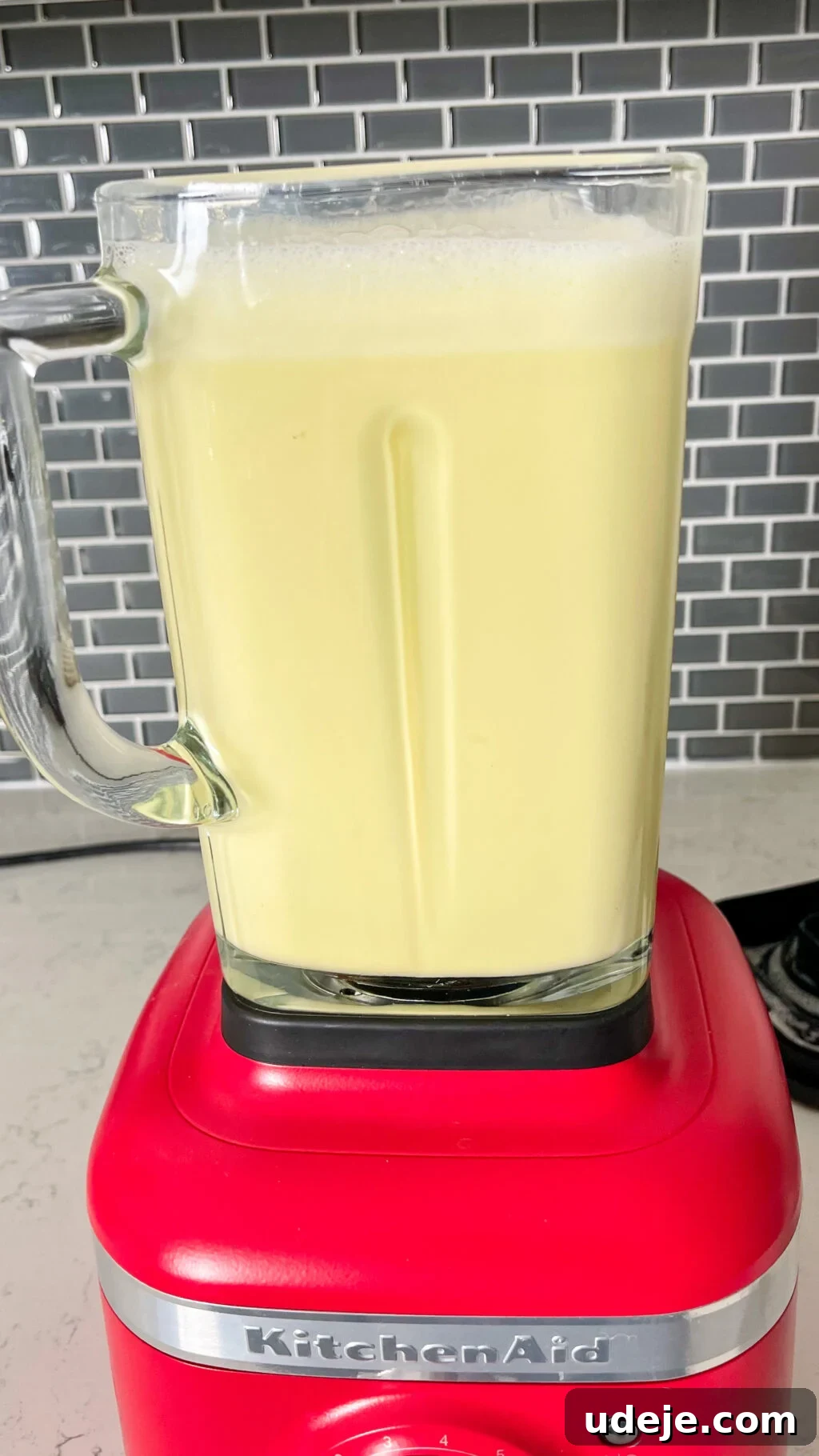Creamy Condensed Milk Creme Caramel 13 blended creme caramel mixture in a glass jug with a red bottom and a dark grey tiled backsplash