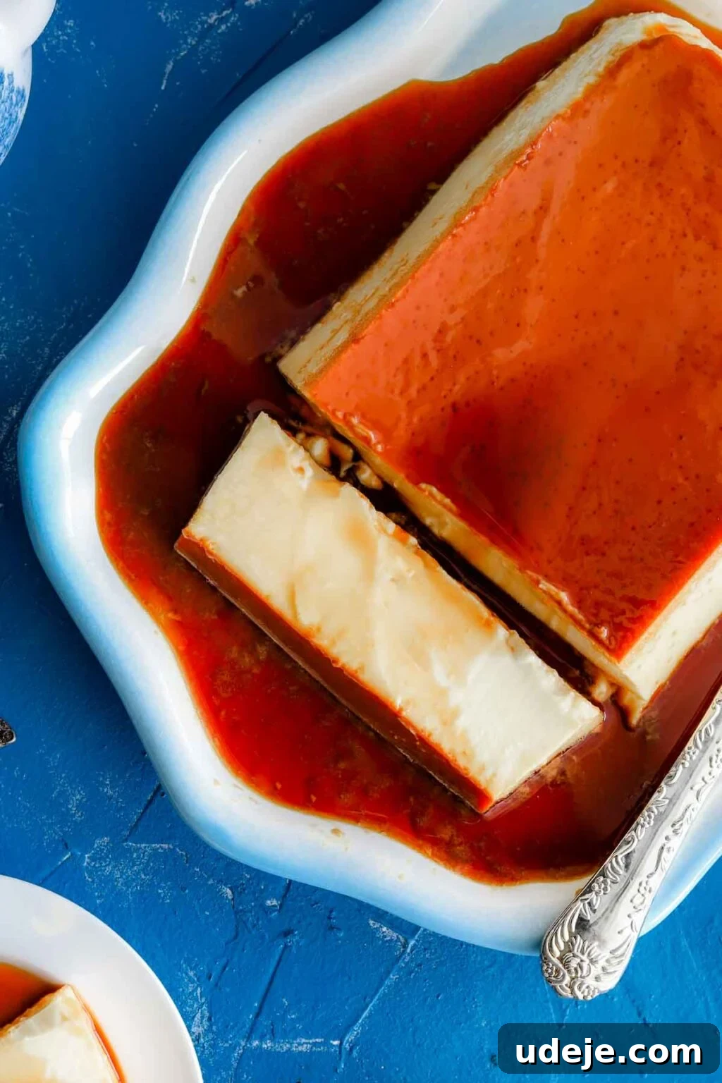 Creamy Condensed Milk Creme Caramel 3 sliced creme caramel on a blue rimmed dish with a serving knife on the side on a blue background