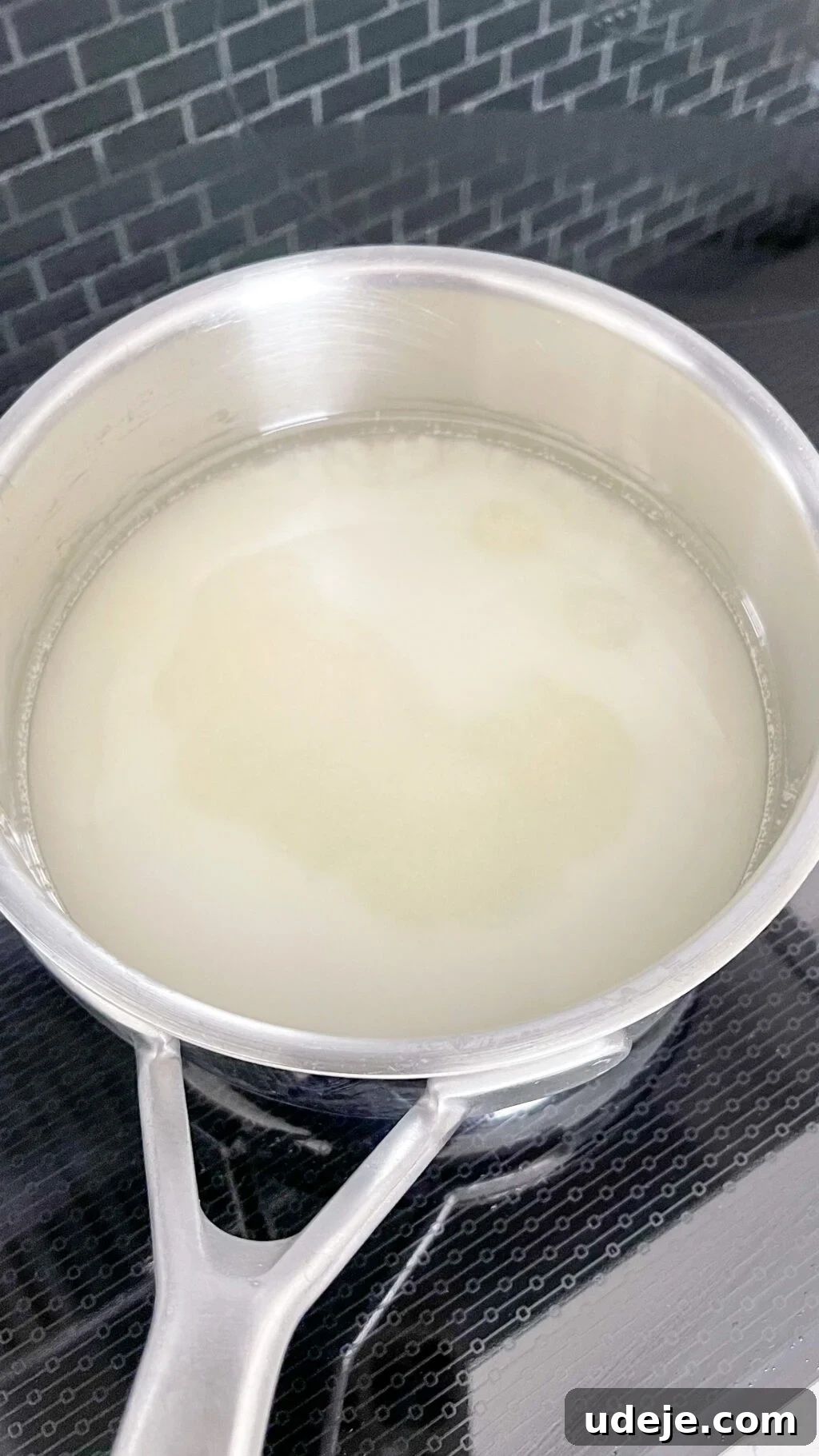 Creamy Condensed Milk Creme Caramel 5 water and sugar in a steel saucepan on a dark coloured stovetop