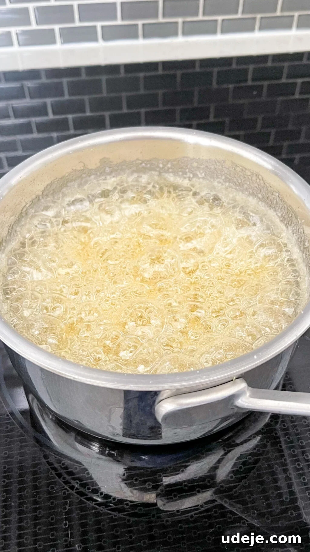Creamy Condensed Milk Creme Caramel 6 light yellow boiling water and sugar in a steel saucepan on a dark coloured stovetop