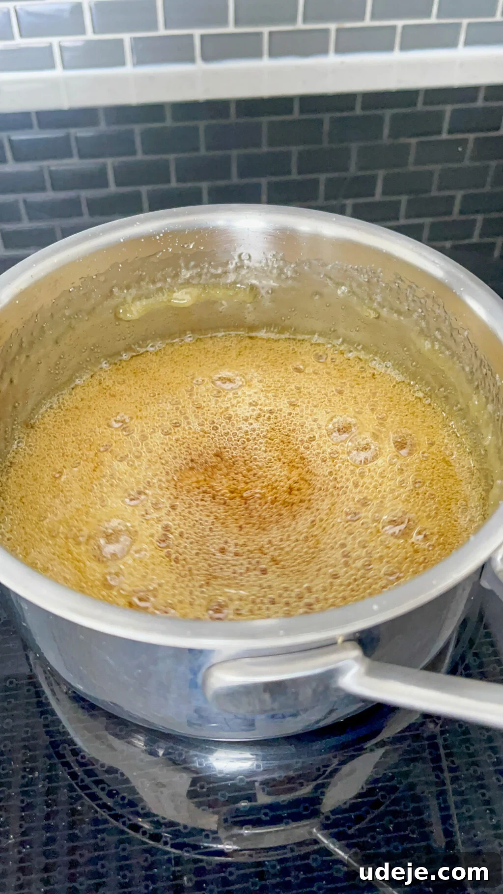 Creamy Condensed Milk Creme Caramel 7 deeper golden simmering water and sugar in a steel saucepan on a dark coloured stovetop