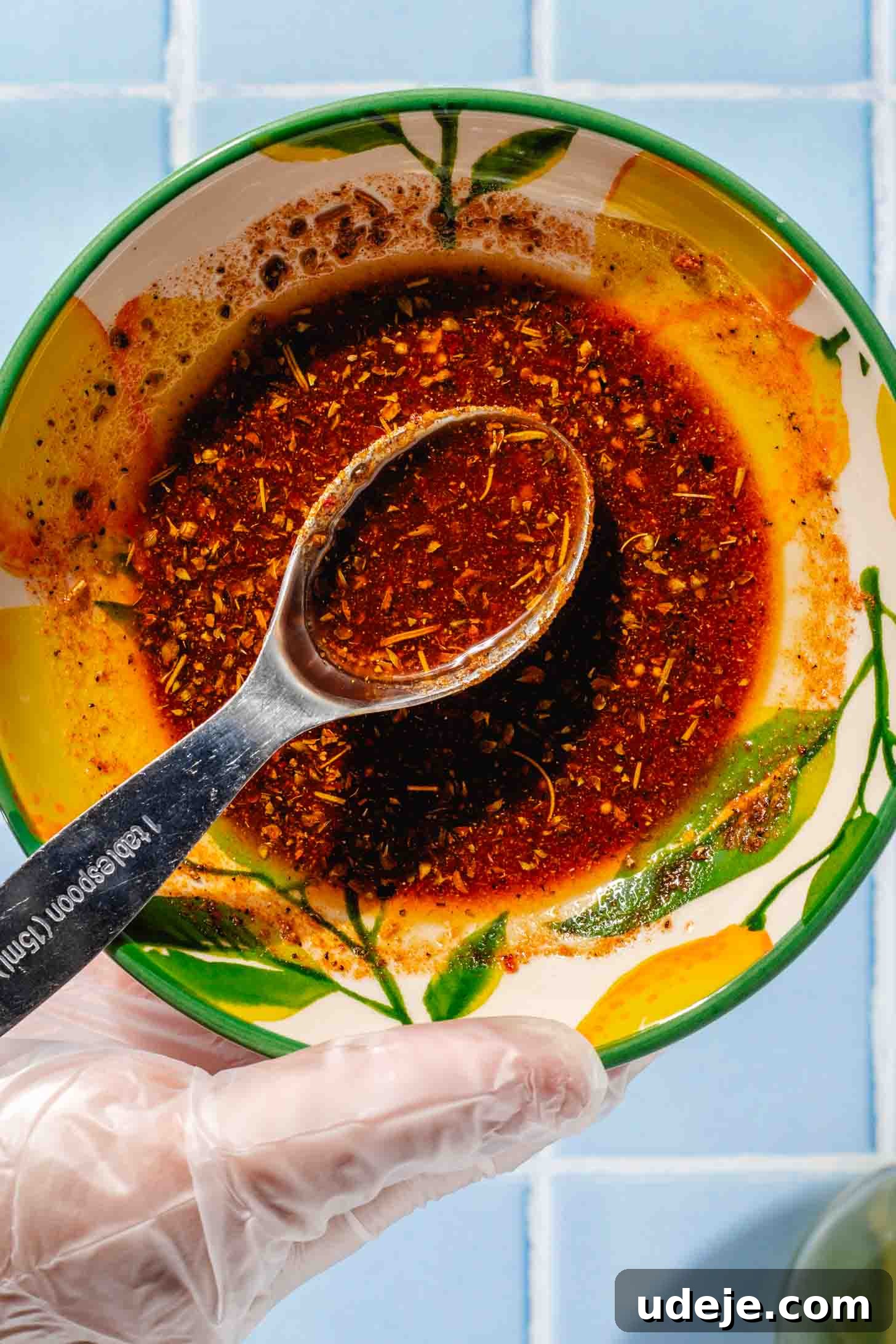 Crispy and Juicy Air Fryer Whole Chicken in 60 Minutes 4 Reddish marinade for airfryer whole chicken in a yellow and green bowl with a measuring spoon inside